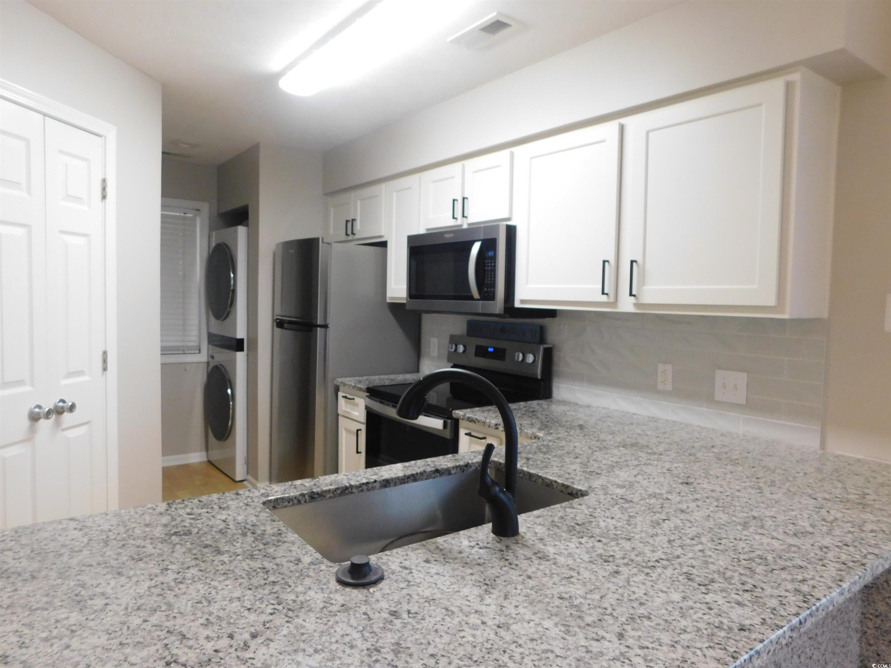 517 White River Drive, Unit BUILDING 22 G Myrtle Beach, SC 29579 - Photo 5 of 17 Kitchen featuring appliances with stainless steel finishes, light stone counters, decorative backsplash, and white cabinetry