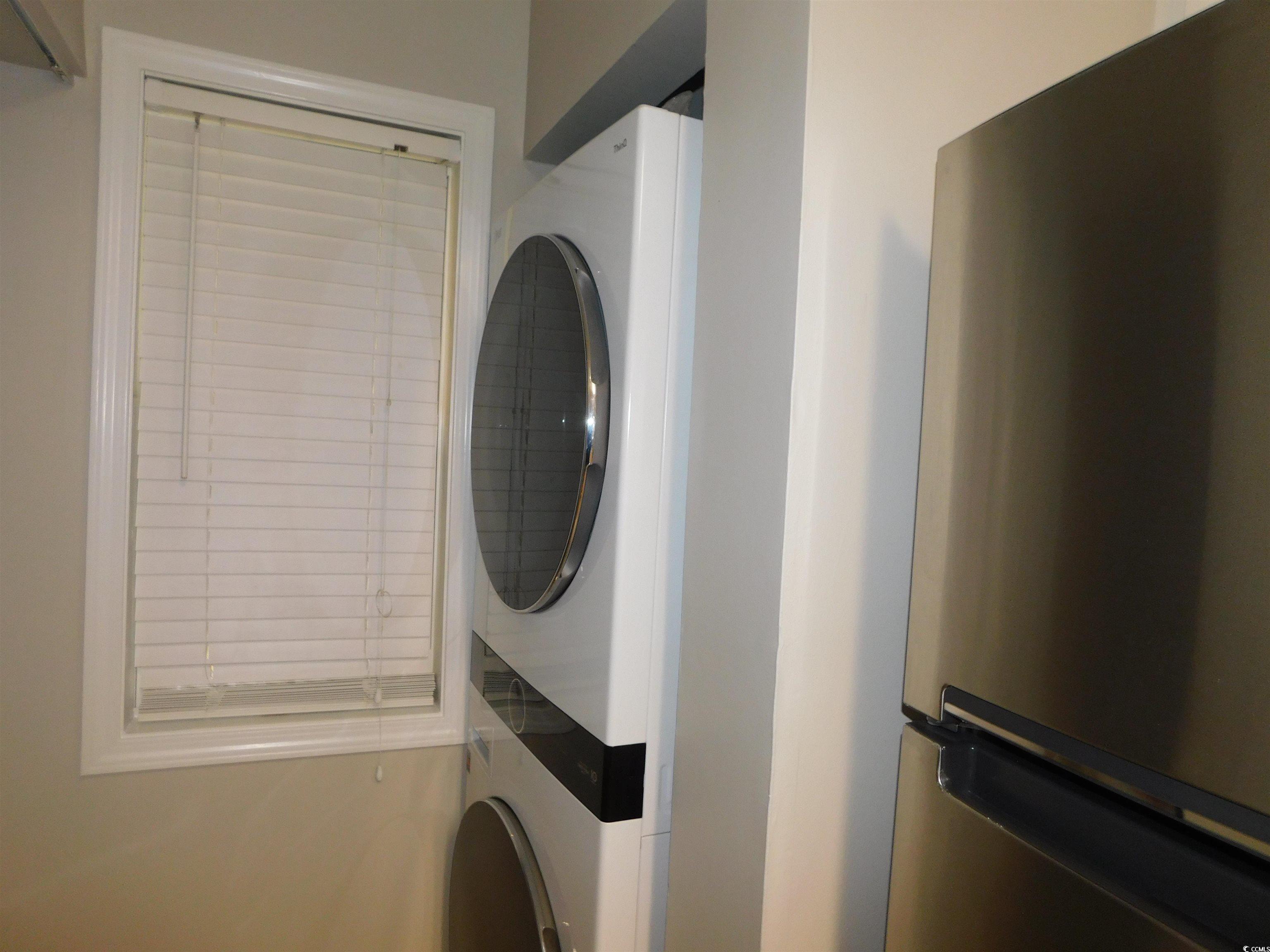 517 White River Drive, Unit BUILDING 22 G Myrtle Beach, SC 29579 - Photo 6 of 17 Kitchen featuring range with electric cooktop, light stone counters, white cabinets, stacked washer / dryer, and stainless steel microwave