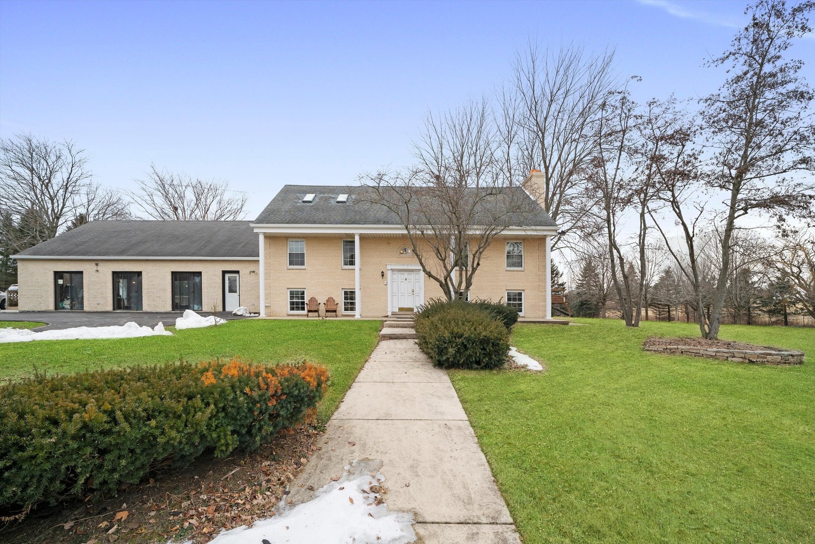 a front view of a house with a garden and trees