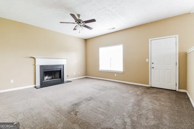 an empty room with windows and fan