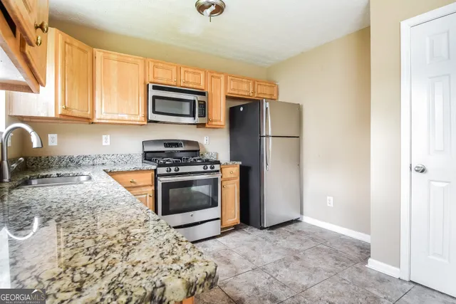 a kitchen with granite countertop a refrigerator stove top oven a sink and dishwasher