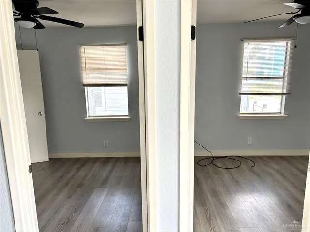 an empty room with wooden floor and windows
