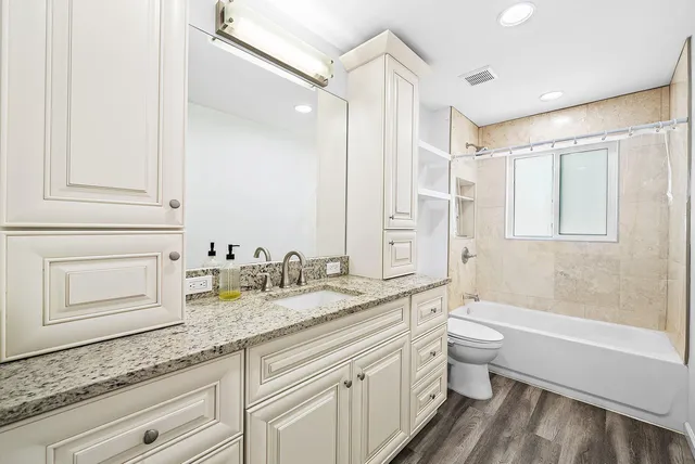a bathroom with a granite countertop sink a toilet and bathtub