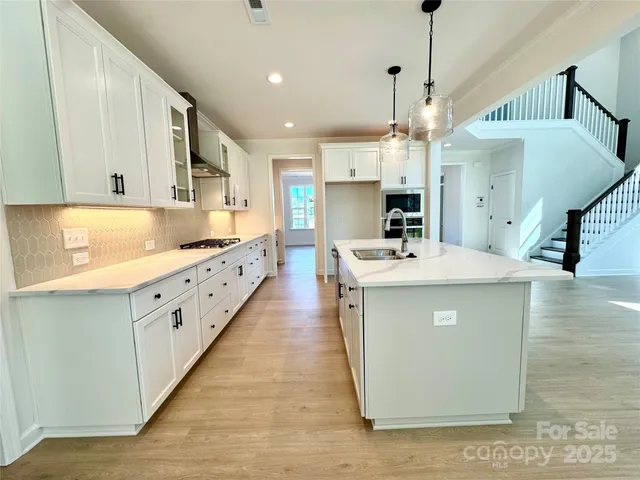a kitchen with kitchen island granite countertop a sink a counter top space cabinets and stainless steel appliances