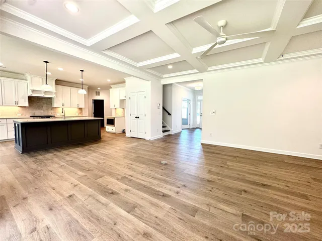 a view of a kitchen with kitchen island a sink wooden floor and a counter top space