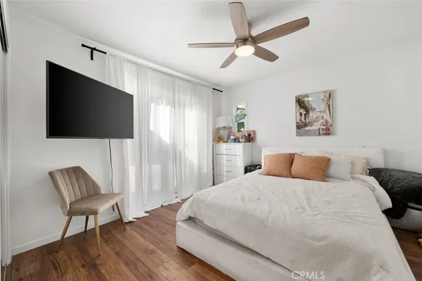 a bedroom with a bed a flat screen tv and a chair