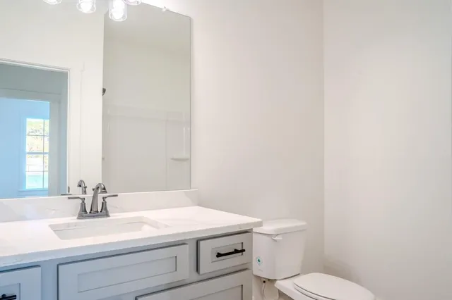 a bathroom with a granite countertop toilet and a sink