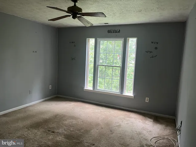 an empty room with a window and a fan