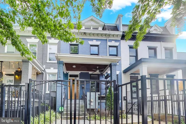 a view of a house with wooden fence and a large tree