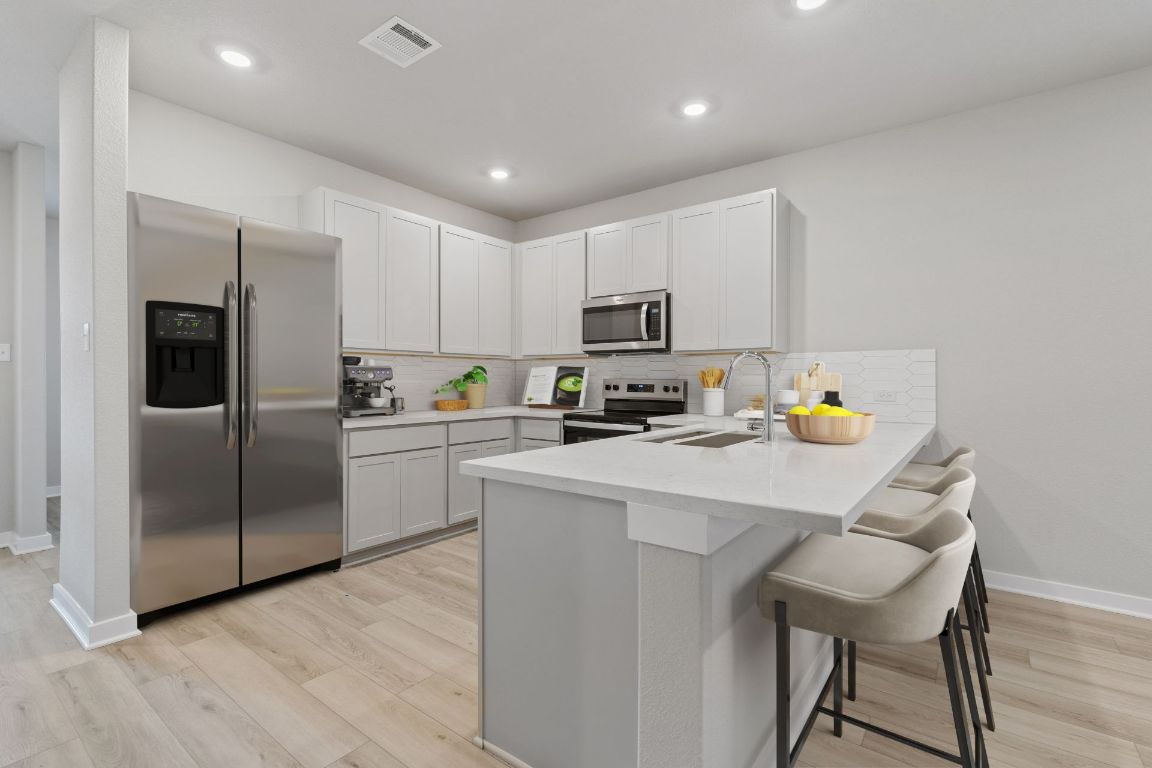 212 Lazy Lizzy Road Jarrell, TX 76537 - Photo 3 of 30 a kitchen with a sink a microwave a refrigerator and cabinets