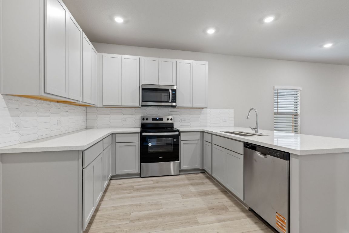 212 Lazy Lizzy Road Jarrell, TX 76537 - Photo 7 of 30 a kitchen with stainless steel appliances granite countertop a sink and stove top oven