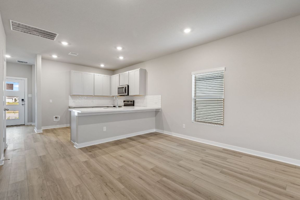 212 Lazy Lizzy Road Jarrell, TX 76537 - Photo 9 of 30 a view of kitchen with granite countertop refrigerator oven sink and white cabinets with wooden floor