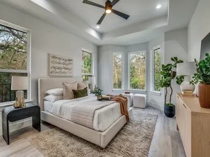 a bedroom with a large bed a potted plant and windows