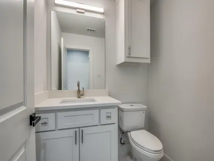 a bathroom with a toilet sink vanity and mirror