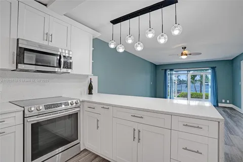 a kitchen with granite countertop white cabinets stainless steel appliances and a window