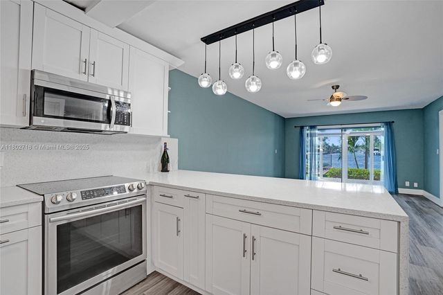 a kitchen with granite countertop white cabinets stainless steel appliances and a window