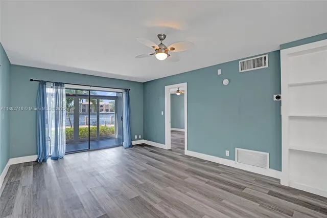 a view of an empty room with a window and wooden floor