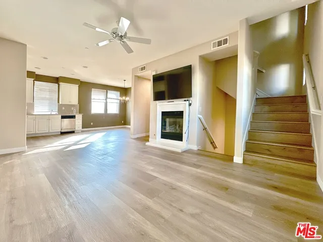 a view of a livingroom with a fireplace a ceiling fan and windows