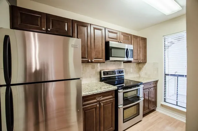 a kitchen with stainless steel appliances granite countertop a refrigerator a stove top oven a sink and dishwasher