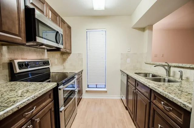 a kitchen with stainless steel appliances granite countertop a stove a sink and a microwave