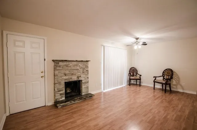 a view of an empty room with fire place and wooden floor