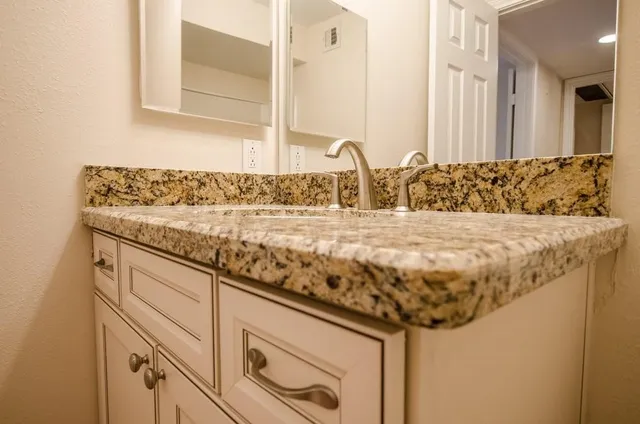 a bathroom with a granite countertop sink and a mirror
