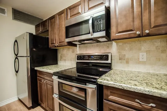 a kitchen with stainless steel appliances granite countertop a stove microwave and refrigerator