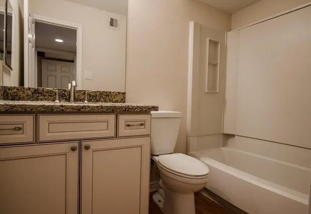 a bathroom with a granite countertop toilet sink and mirror