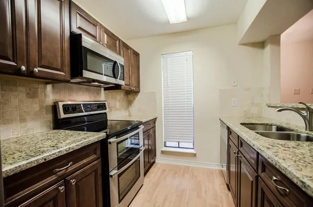 a kitchen with stainless steel appliances granite countertop a stove microwave and sink