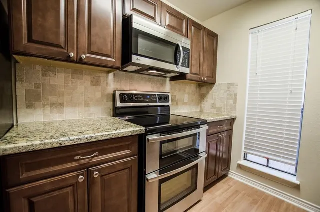 a kitchen with granite countertop cabinets stainless steel appliances and wooden floor