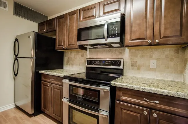 a kitchen with stainless steel appliances granite countertop a stove microwave and refrigerator