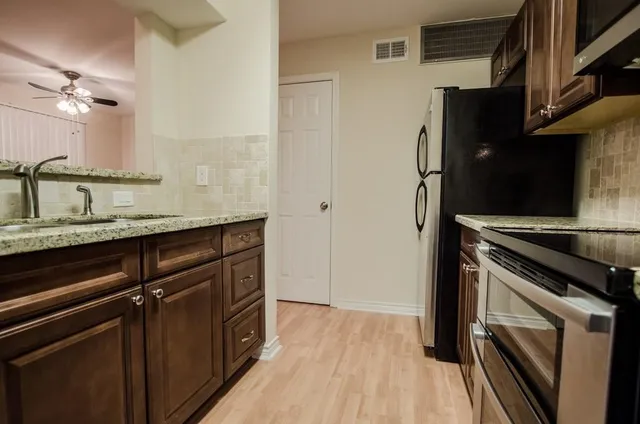 a kitchen with granite countertop a sink cabinets and stainless steel appliances