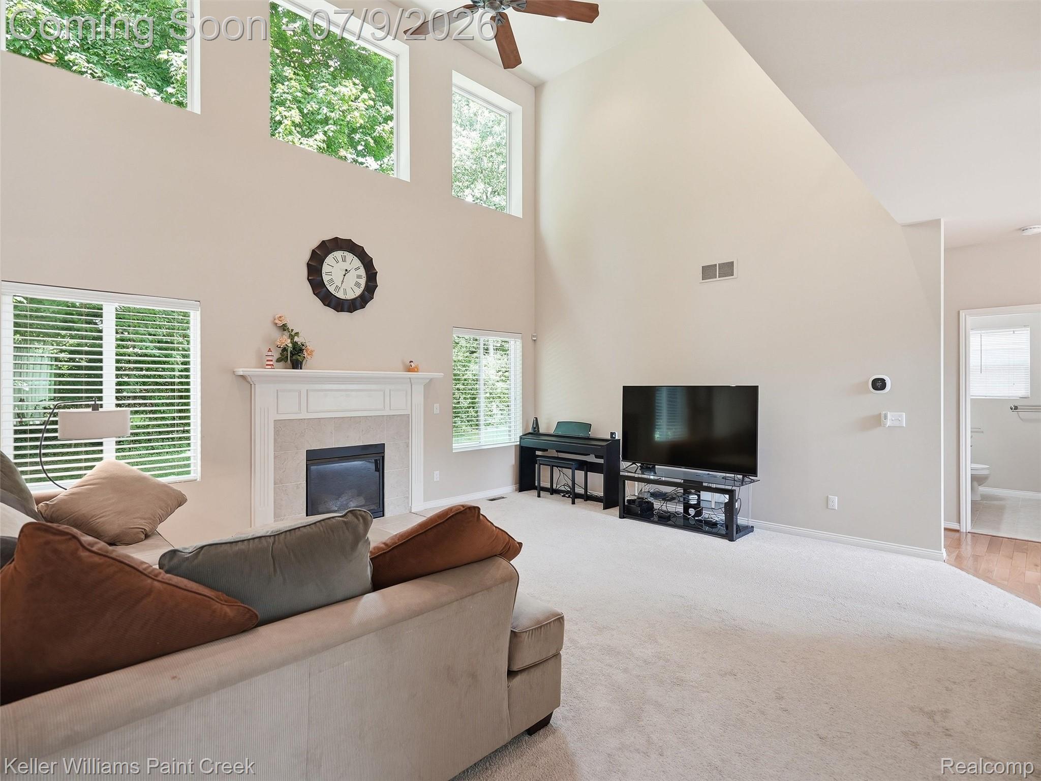 846 Monterey Ln. Rochester, MI 48307 - Photo 12 of 52 Vaulted living room with a ceiling fan, gas fireplace featuring a tile surround and white mantel, and high transom windows