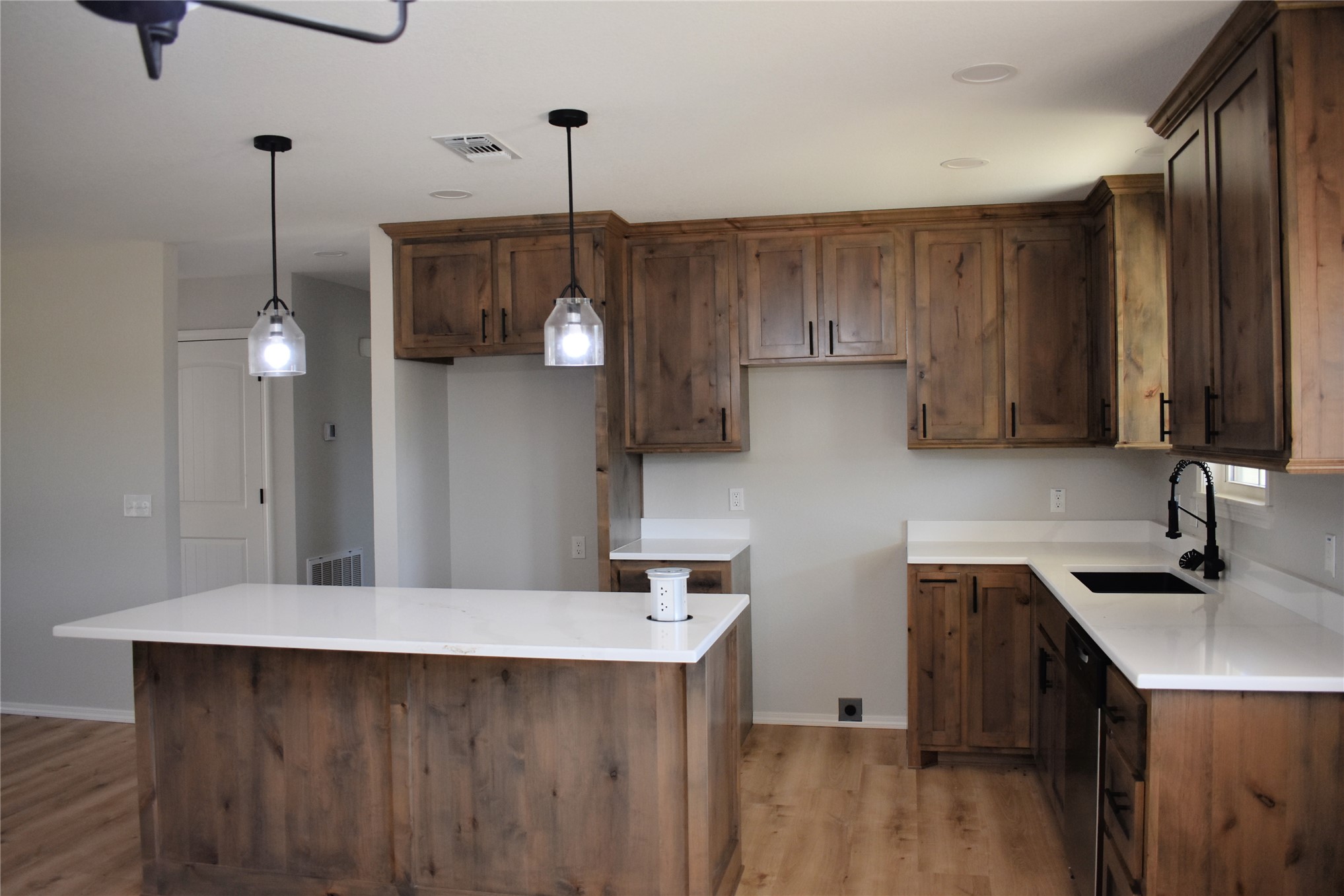 2911 East 2090 Road Hugo, OK 74743 - Photo 7 of 22 Kitchen featuring wood-finish cabinetry, white countertops, a large island with pendant lighting, a black sink, and wood-finish flooring