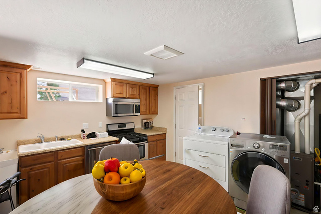 580 North 300 East Logan, UT 84321 - Photo 67 of 74 Kitchenette featuring wood-finish cabinetry, light-toned countertops, and a stainless steel appliance suite including a gas range and microwave
