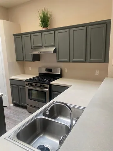 a view of an empty room with wooden floor fridge and a window