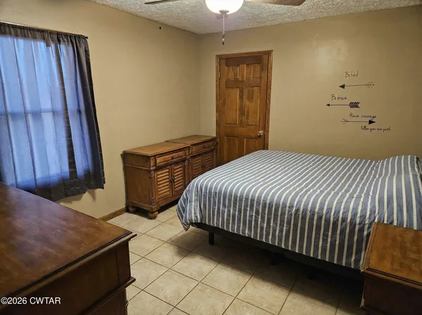 a bedroom with a bed and a flat tv screen on the dresser