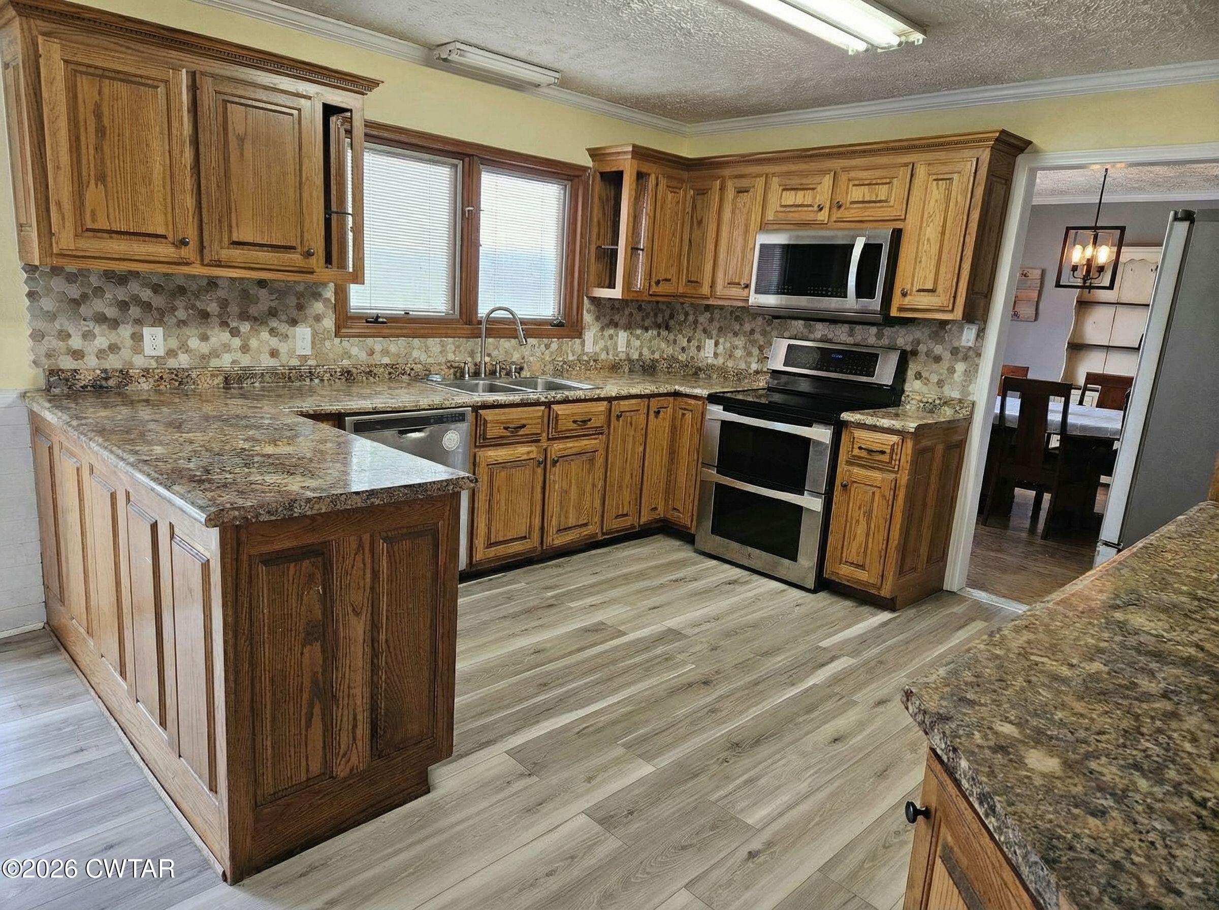 103 Spring Creek Law Road Jackson, TN 38305 - Photo 4 of 35 a kitchen with stainless steel appliances granite countertop a stove top oven a sink dishwasher and a microwave oven with large wooden cabinets