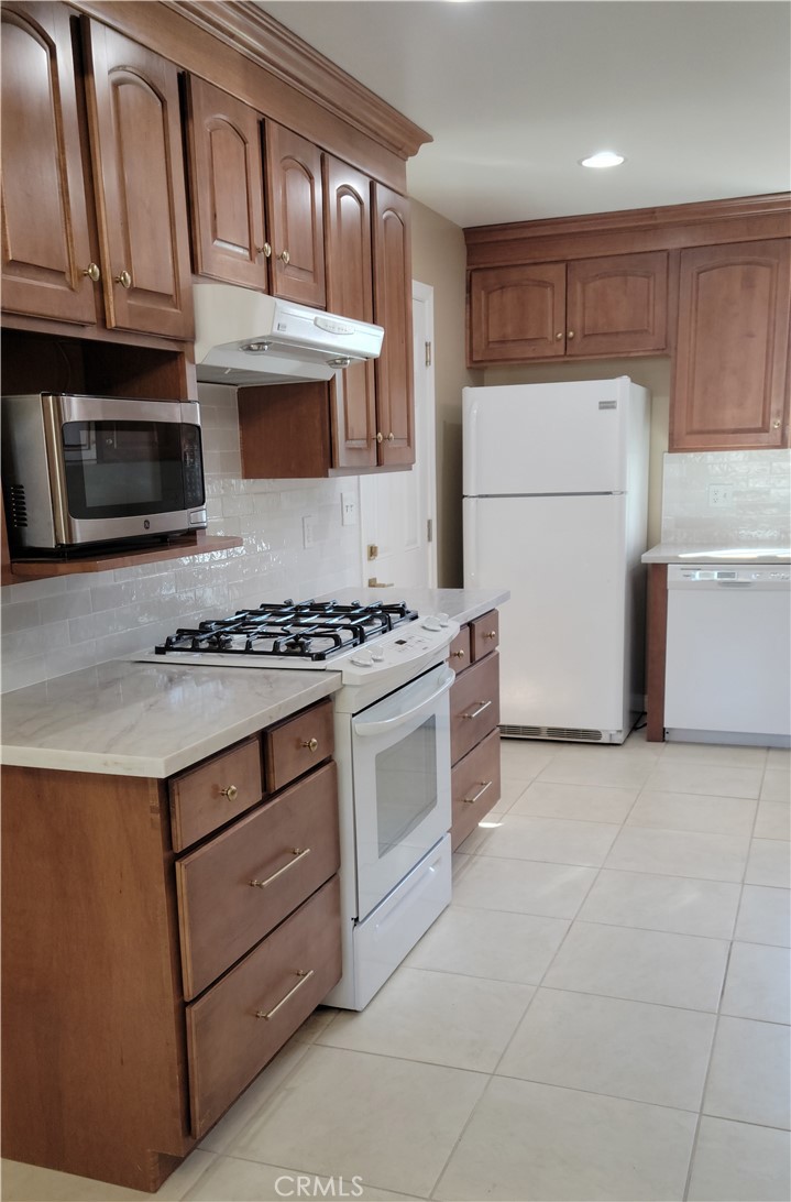 1309 Stillman Avenue Redlands, CA 92374 - Photo 3 of 23 a kitchen with granite countertop a stove top oven a sink dishwasher and a refrigerator with wooden cabinets