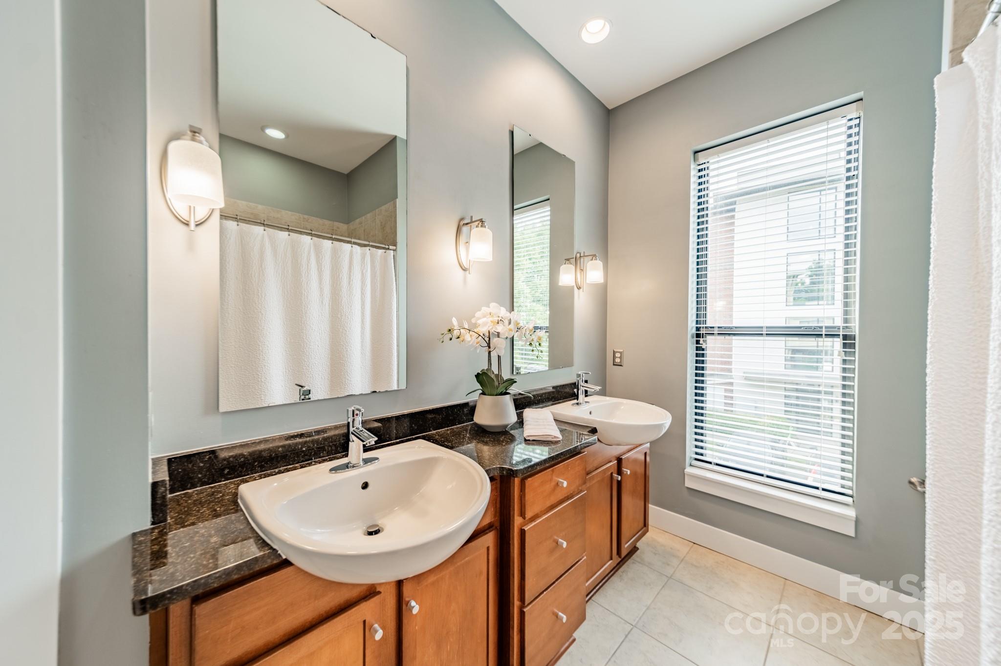 2988 Textile Way Charlotte, NC 28205 - Photo 18 of 36 a bathroom with a double vanity sink a mirror and a bathtub