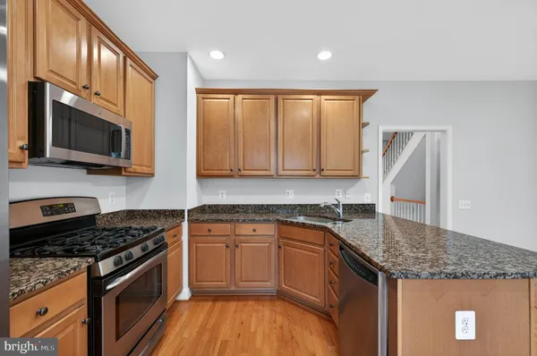 a kitchen with stainless steel appliances granite countertop a stove a sink and a microwave
