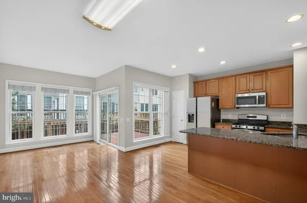 a view of a kitchen with furniture a ceiling fan and wooden floor
