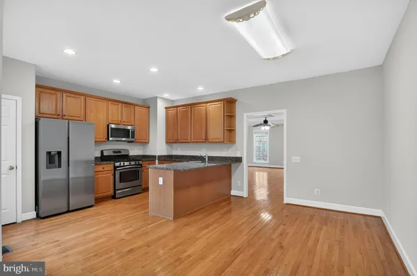 a large kitchen with stainless steel appliances granite countertop a stove a refrigerator a sink a microwave and wooden floor
