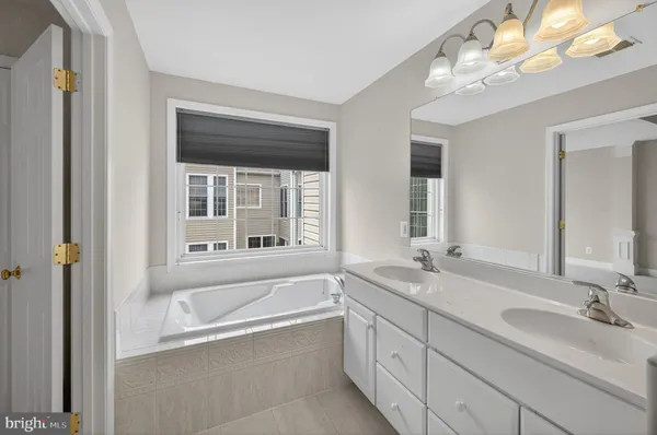 a bathroom with a tub a sink and a large mirror