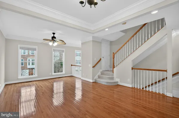 a view of an empty room with wooden floor and a chandelier