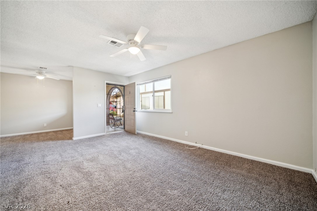 5733 Smoke Ranch Road, Unit D Las Vegas, NV 89108 - Photo 3 of 14 Carpeted empty room with a textured ceiling and a ceiling fan