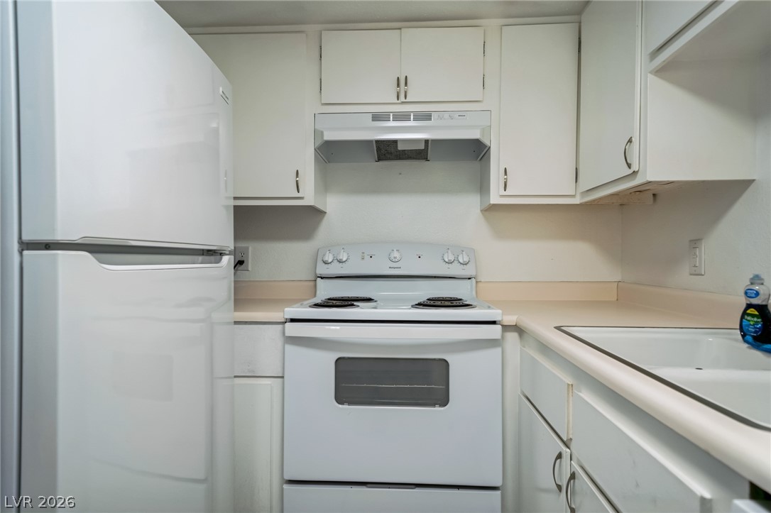 5733 Smoke Ranch Road, Unit D Las Vegas, NV 89108 - Photo 7 of 14 Kitchen with white appliances, white cabinets, and light countertops