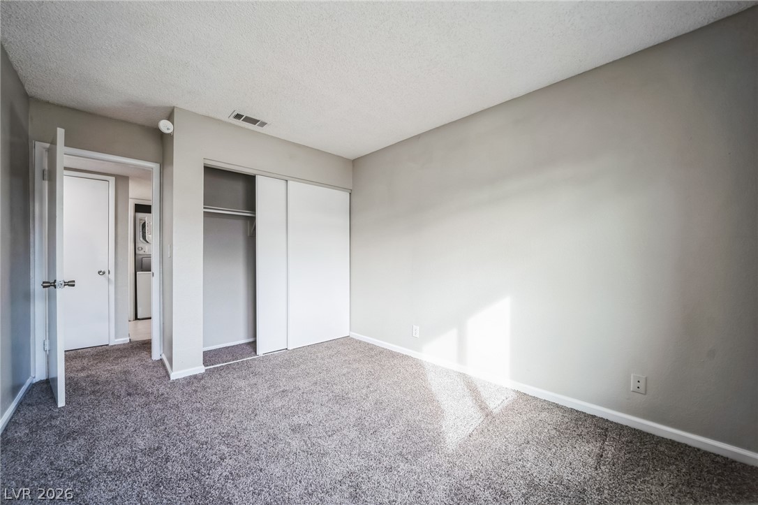 5733 Smoke Ranch Road, Unit D Las Vegas, NV 89108 - Photo 8 of 14 Unfurnished bedroom with carpet, a textured ceiling, and a closet