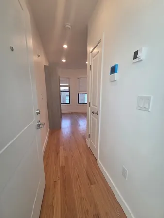 a view of a hallway with wooden floor and a refrigerator
