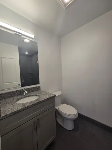 a bathroom with a granite countertop sink a toilet and a mirror